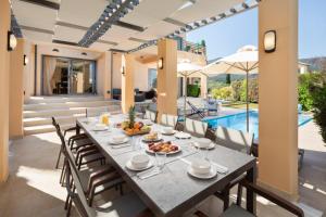 a dining room with a table and chairs and a pool at Villa Serena, Eastern Corfu in Kato Korakiana