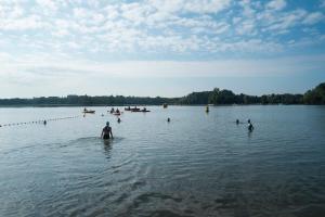 Un groupe de gens nageant dans un grand lac dans l'établissement CityKamp Angers, à Angers