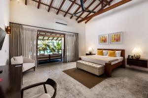 a bedroom with a bed and a couch and a chair at Lantern Boutique Hotel by Reveal in Mirissa