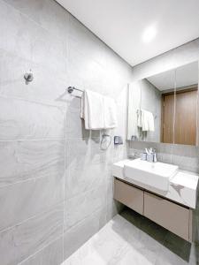 uma casa de banho branca com um lavatório e um espelho em Apartment 1BR FL28th-Ruby-Vinhomes Ocean Park em Hanói