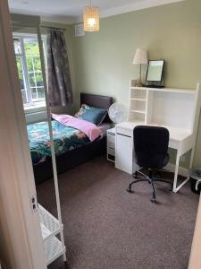 um quarto com uma cama e uma secretária com um computador em Harrow Town Centre 3 Bed Flat - Sleep up to 5 people, close to London Underground em Harrow