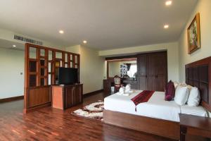 Arawan Riverside Hotel في باكسي: غرفة نوم كبيرة بها سرير وتلفزيون