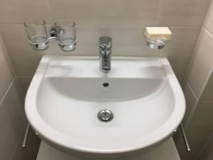 a white sink in a bathroom with two drinking glasses at Appartement meublé proche de la Gare de Lausanne 12 in Lausanne