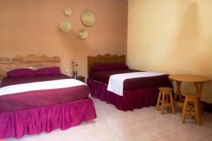 a bedroom with two beds and a table and two stools at Hotel Israel in Guastatoya