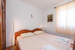 una camera da letto con un letto con lenzuola bianche e una finestra di Apartment Valkovic a Baška