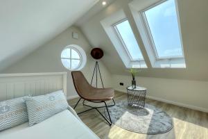een zolderkamer met een bed en een stoel bij Vista 5, mit Balkon und drei Schlafzimmern in Greetsiel