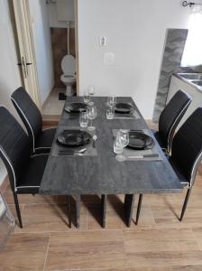 a black dining table with black chairs and wine glasses at Apartman Selce in Selce