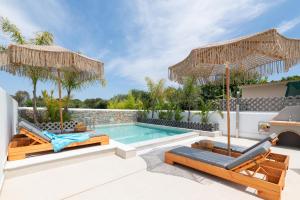 a villa with a swimming pool with two chairs and umbrellas at Aqua Villa Faliraki in Faliraki