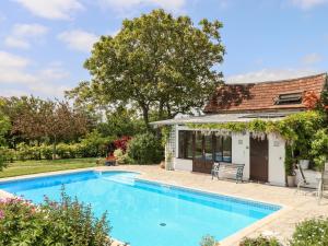 a swimming pool in front of a house at Shillings Cottage in Cullompton
