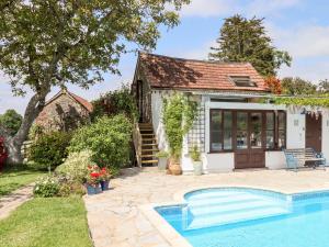 a cottage with a swimming pool in front of a house at Shillings Cottage in Cullompton