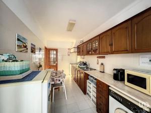 uma cozinha com armários de madeira e uma bancada em T2 ideal para descansar e com Espanha ao lado em Vila Real de Santo António mais 5 fotografias
