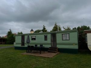 a green trailer with a table and chairs in a yard at Autocamp Free Star - Mobilheimy in Strachotín