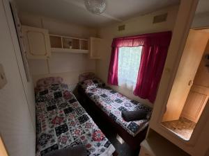 Habitación pequeña con 2 camas y ventana en Autocamp Free Star - Mobilheimy, en Strachotín