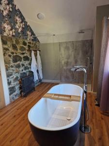 a bath tub in a room with a stone wall at Blackberry Barn in Ballymena