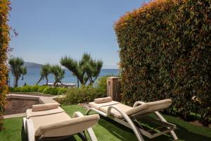 a couple of chairs sitting on the grass next to a hedge at Caresse, a Luxury Collection Resort & Spa, Bodrum in Bitez