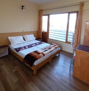 a bedroom with a bed with a large window at Gonbo Guest House in Leh