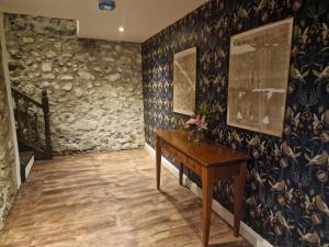een hal met een houten tafel in een kamer met een stenen muur bij Blackberry Barn in Ballymena