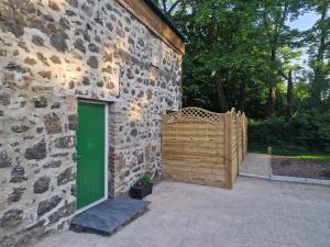 um edifício com uma porta verde e um portão de madeira em Blackberry Barn em Ballymena