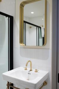 ein Badezimmer mit einem weißen Waschbecken und einem Spiegel in der Unterkunft Trendy London Home GS1 in London