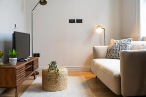 ein Wohnzimmer mit einem Sofa und einem TV in der Unterkunft Trendy London Home GS1 in London