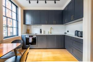 eine Küche mit dunkelblauen Schränken und einem Tisch in der Unterkunft Trendy London Home GS1 in London