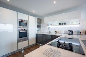 a kitchen with white cabinets and stainless steel appliances at Beach View Breeze Family Holiday Home on the Shore in Pevensey