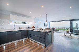 a kitchen with black cabinets and a view of the ocean at Beach View Breeze Family Holiday Home on the Shore in Pevensey