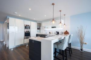 a kitchen with white cabinets and a kitchen island with bar stools at Beach View Breeze Family Holiday Home on the Shore in Pevensey +47 photos