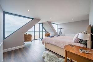 a bedroom with a bed and a table and windows at Beach View Breeze Family Holiday Home on the Shore in Pevensey