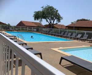 una piscina con sillas y una persona en el agua en Pavillons 7 et 56 Narbonne Plage, en Narbonne-Plage