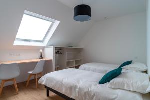 1 Schlafzimmer mit 2 Betten, einem Schreibtisch und einem Fenster in der Unterkunft Ti Menhir - Charmante maison pour 6 avec jardin in Plomelin