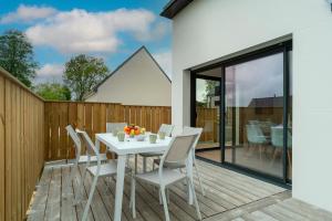 een witte tafel en stoelen op een houten terras bij Ti Menhir - Charmante maison pour 6 avec jardin in Plomelin