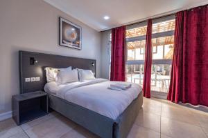 a bedroom with a large bed with red curtains at Villa Magnum in Douala