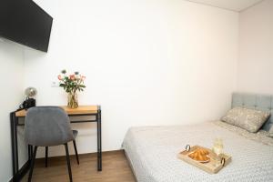 een slaapkamer met een bed, een bureau en een stoel bij Downhill Apartment on the Groundfloor in Kaunas