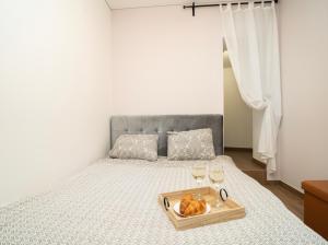 een bed met een dienblad met brood en twee glazen wijn bij Downhill Apartment on the Groundfloor in Kaunas
