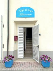 a white building with two blue pots of flowers at Affittacamere I Gigli di Mare in Marina di Bibbona