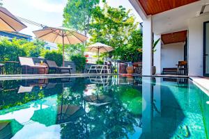 una piscina con sombrilla, sillas y mesas en Hoi An Majestic Villa, en Hoi An