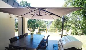 um pátio com uma mesa e um guarda-chuva em Le Fusain - Maison climatisée pour 6 em Pont-Aven
