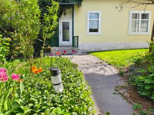a house with a garden with flowers and a walkway at Charmantes Haus mit Terrasse und großem Garten in Langenzersdorf