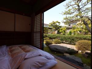 金澤的住宿－Ryokan Karasawa，一张位于带大窗户的房间内的床铺