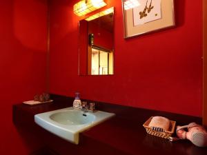 Baño rojo con lavabo y espejo en Ryokan Karasawa, en Kanazawa