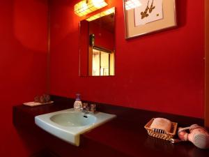 a red bathroom with a sink and a mirror at Ryokan Karasawa in Kanazawa