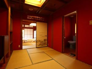 a hallway with red walls and a door to a bathroom at Ryokan Karasawa in Kanazawa