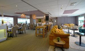 restauracja z kanapą, stołami i krzesłami w obiekcie Hôtel Best Western The Wish Versailles w mieście Guyancourt