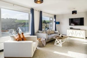 a living room with white furniture and a large window at Holiday Home Churchfields - Stunning Views in Dartmouth
