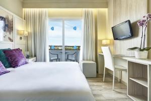 a hotel room with a bed and a desk and a window at Grupotel Maritimo in Port d'Alcudia