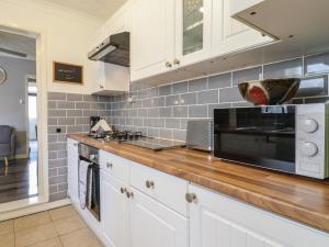 a kitchen with white cabinets and a black microwave at 122 Morton Road in Lowestoft