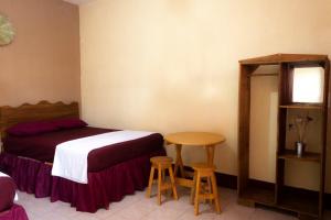 a bedroom with a bed and a table and two stools at Hotel Israel in Guastatoya