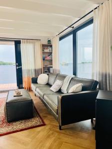 een woonkamer met een bank en een groot raam bij Surla Houseboat "Walvis" Kagerplassen with tender 
