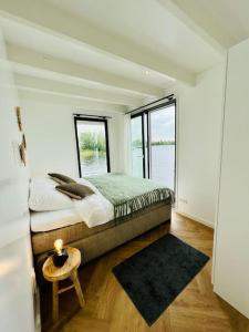 een slaapkamer met een bed en een groot raam bij Surla Houseboat "Walvis" Kagerplassen with tender 